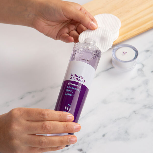 Photo of a person pouring the cleansing tonic on a cotton pad